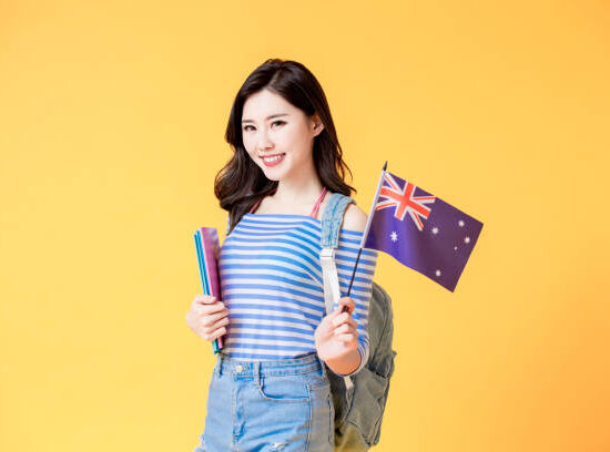 asian female student smile and look to you with Australian flag isolated yellow background